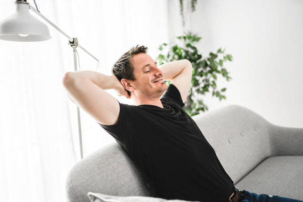 A Relaxing man and dreaming on sofa at home with arm behind his head - Fotoğraf, Görsel