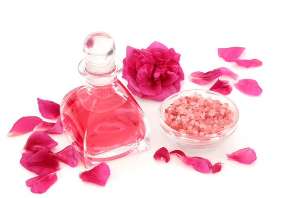 Rosewater in art deco glass bottle with flower, petals and Himalayan salt for exfoliation beauty treatment. Natural skincare concept to restore skin ph balance. On white background. Rosa rugosa.  - Foto, Imagem
