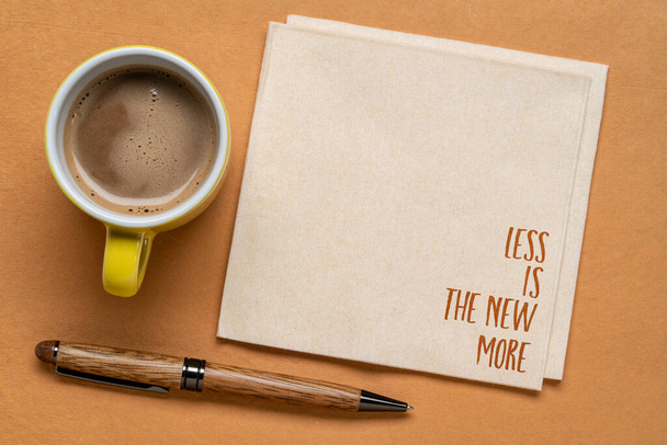 less is the new more - minimalism concept, handwriting on a napkin with a cup of coffee - Foto, Imagen