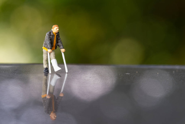 Miniature people , Full length view of a man with broken leg is using crutch For Walking - Photo, Image