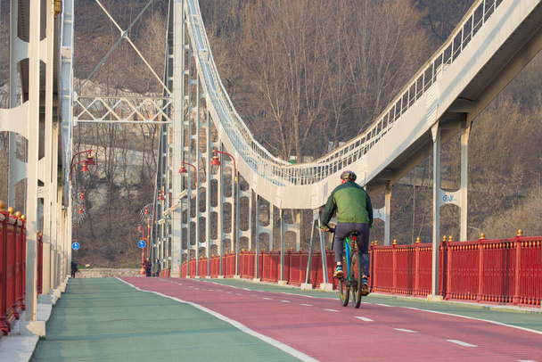 KYIV, UKRAINE - 2. toukokuuta 2022: Mies pyöräilee Dnipro-joen ylittävällä sillalla Kiovassa, Ukrainassa. Aktiivinen elämäntapa. - Valokuva, kuva