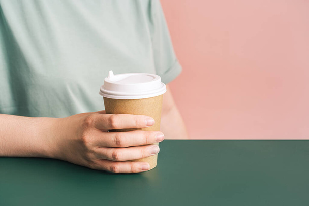 Dziewczyna ze szklanką kawy w rękach siedzi przy zielonym stole - Zdjęcie, obraz