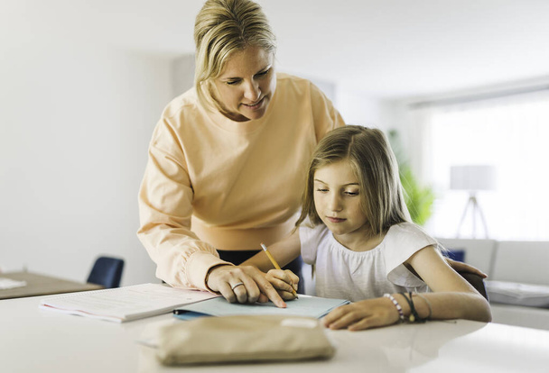 Mom helping kid with homework at home - Foto, immagini