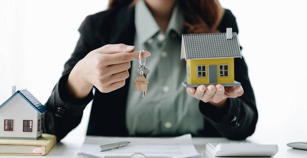 Agent nieruchomości prezentuje kredyt mieszkaniowy i wysyła klucze do klienta po podpisaniu umowy do wypożyczalni Ubezpieczenia z zatwierdzonym formularzem nieruchomości - Zdjęcie, obraz