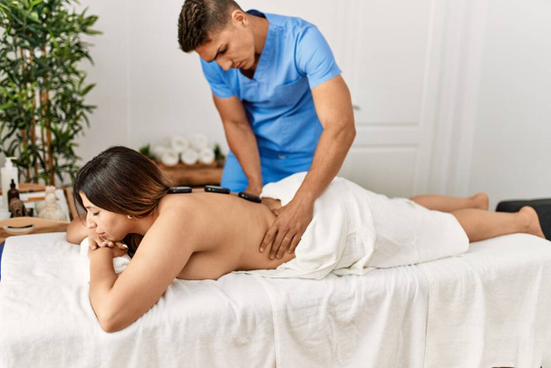 Mujer recibiendo masaje de espalda con piedras negras en el centro de belleza. - Foto, Imagen