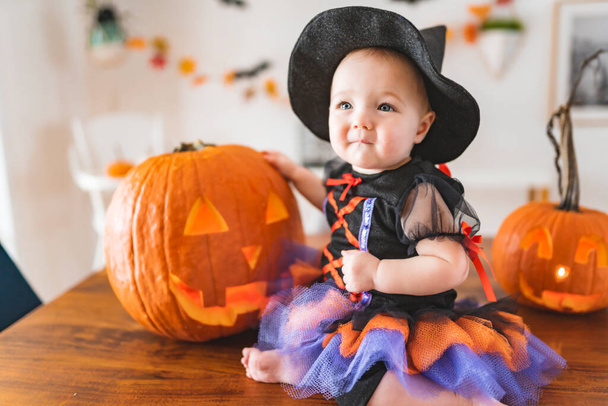 beautiful baby girl in witch halloween costume at home kitchen table - Fotografie, Obrázek