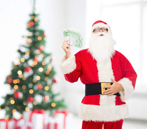 mies puvussa joulupukki eurolla rahaa
 - Valokuva, kuva