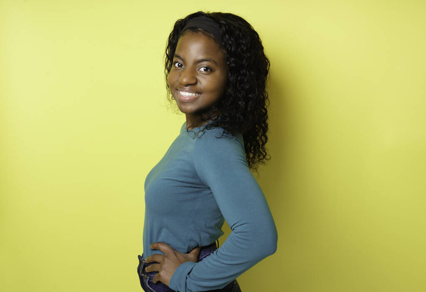 Cheerful African American female with pleasant smile over yellow background - Фото, изображение