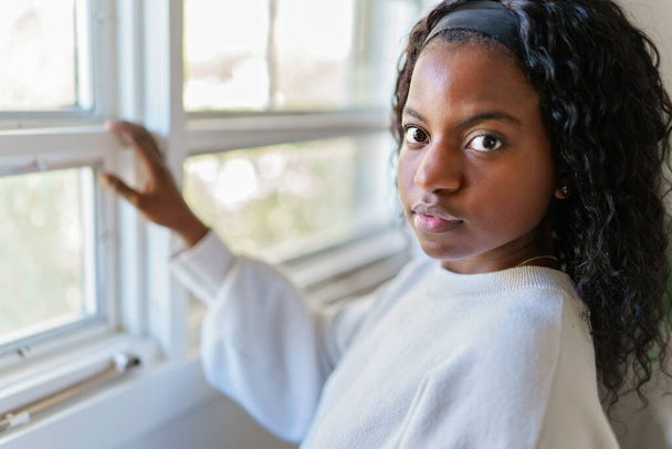 black woman looking out window at home - Photo, image