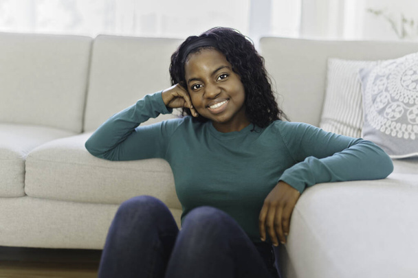 Beautiful African American woman sit on the sofa at home - 写真・画像