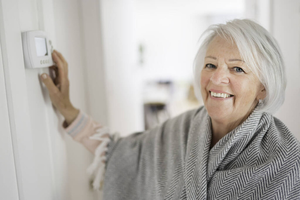 Senior woman adjusting her thermostat at home - Fotografie, Obrázek