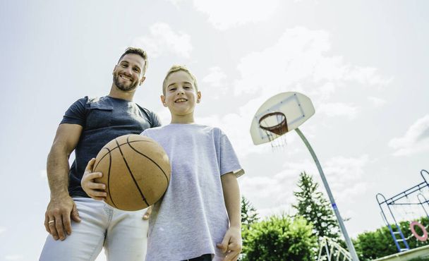 Happy basketball family portrait play this sport on summer season. The father play with boy - 写真・画像