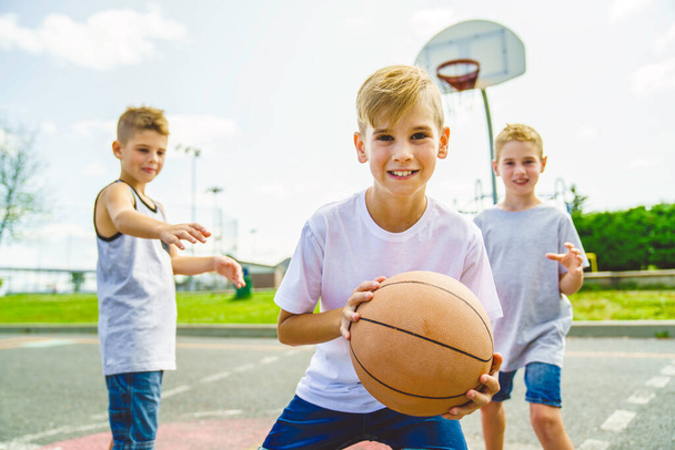 Мальчики играют в баскетбол в летнее время - Фото, изображение