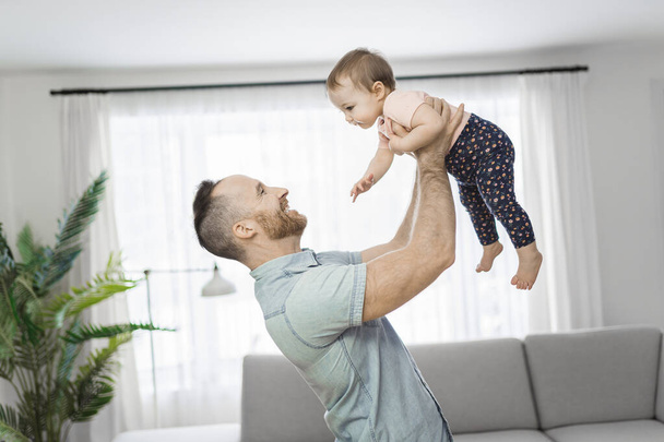 father wit his baby daughter having funny on the living room - 写真・画像
