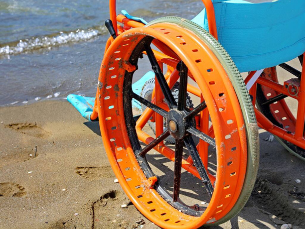 конкретний інвалідний візок з колесами, модифікованими для переміщення на піщаному пляжі біля моря
 - Фото, зображення