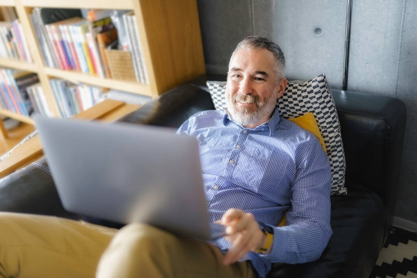 Portrait of handsome man with laptop on sofa - Фото, зображення
