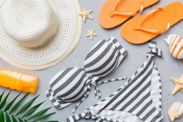 Woman swimwear and beach accessories flat lay top view on colored background Summer travel concept. bikini swimsuit, straw hat and seasheels. Copy space Top view. - Фото, зображення