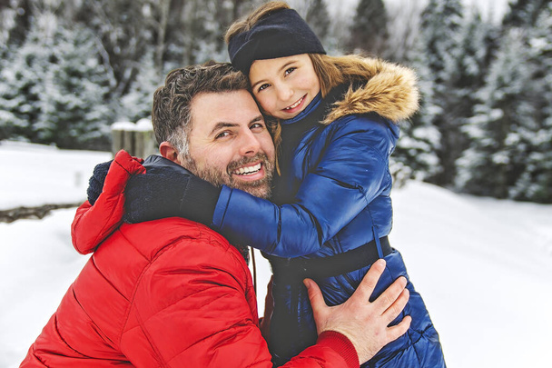 Handsome dad and his daughter are having fun outdoor in winter - Foto, afbeelding