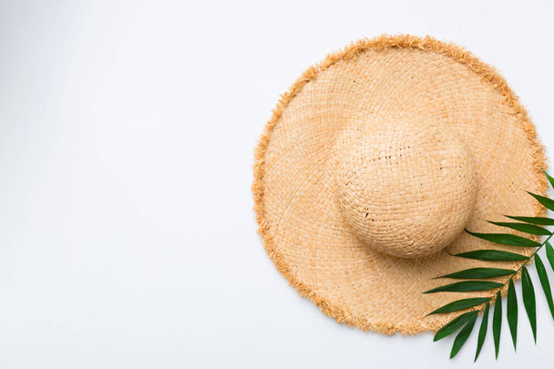 Summer holidays. Summer concept with straw hat and tropical leaf. Flat lay, top view, copy space. - Fotó, kép