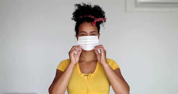 Young African descent woman putting face mask virus prevention, girl crossing arms looking at camera - Zdjęcie, obraz