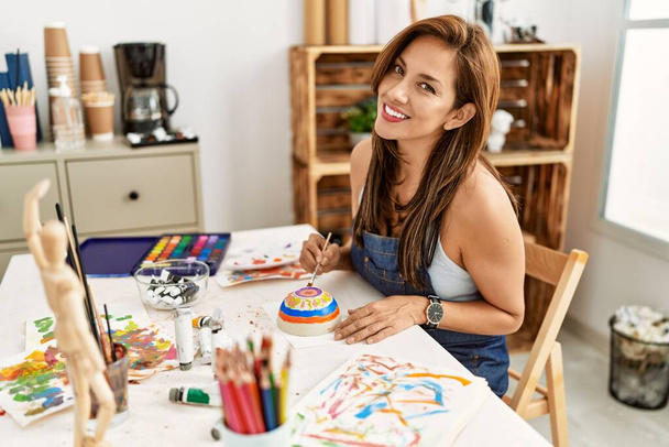 Fiatal spanyol művész nő mosolyog boldog rajz a művészeti stúdióban. - Fotó, kép