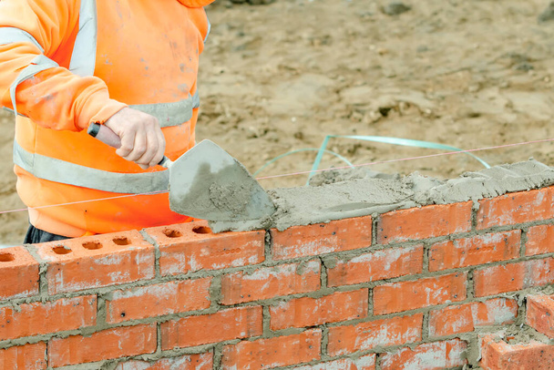 Ladrillo albañil colocando ladrillos en mortero en la nueva construcción de viviendas - Foto, imagen