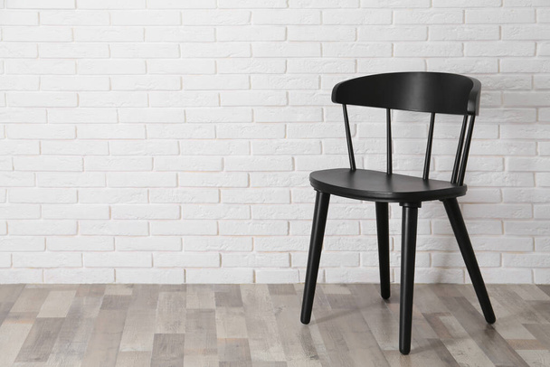 Stylish comfortable black chair near white brick wall, space for text - Photo, image