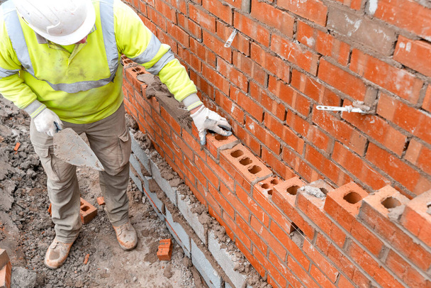 Ladrillo albañil colocando ladrillos en mortero en la nueva construcción de viviendas - Foto, imagen