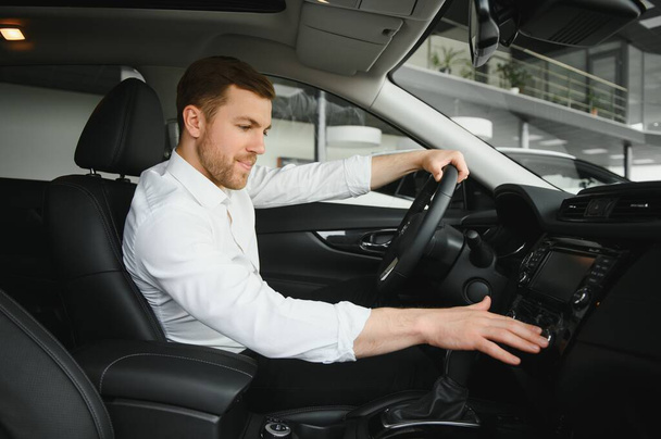 Handsome businessman driving car before buying. - Foto, imagen