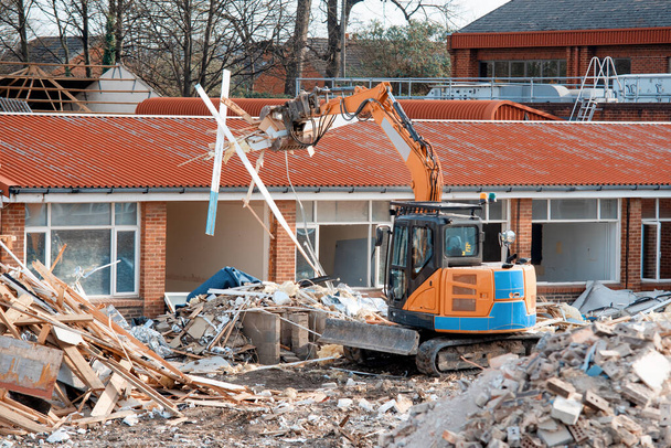 Démolition d'un ancien bâtiment avec une pelle pour céder la place à un nouveau site d'habitation et des tas de décombres - Photo, image
