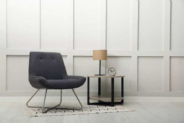 Modern grey armchair and small table near white wall indoors. Space for text - Foto, immagini