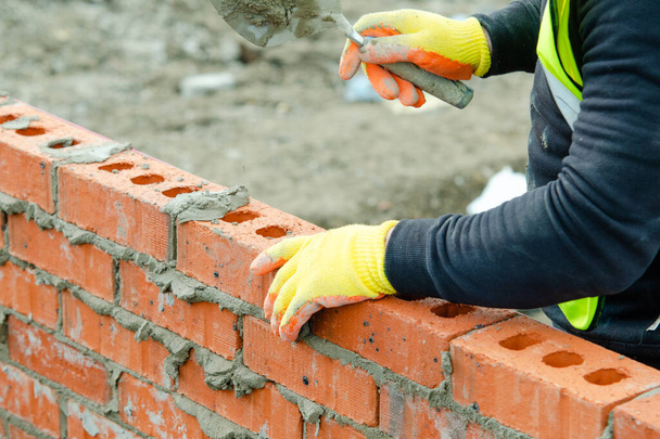 Bricklayer laying bricks on mortar on new residential house construction. Get skiils in construction concept - Foto, Imagen