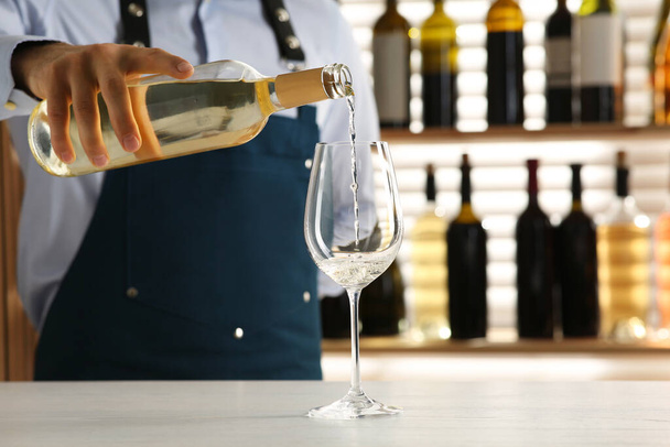 Bartender pouring wine into glass at counter in restaurant, closeup - Foto, Imagen