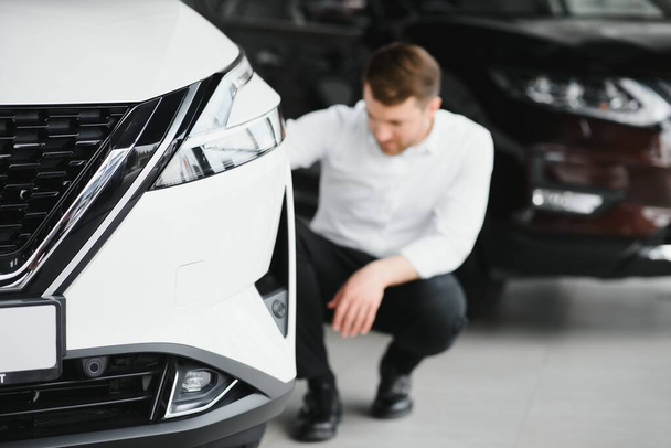 Man adult customer male buyer client wears classic suit white shirt chooses auto wants to buy new automobile touch check car in showroom vehicle salon dealership store motor show indoor. Sales concept - 写真・画像