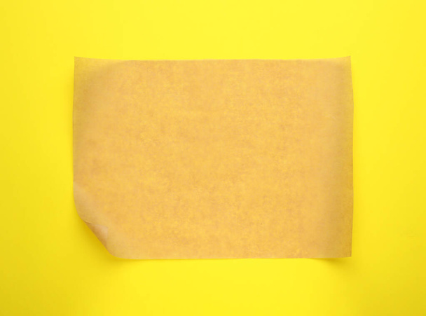 Sheet of brown baking paper on yellow background, top view - Photo, image