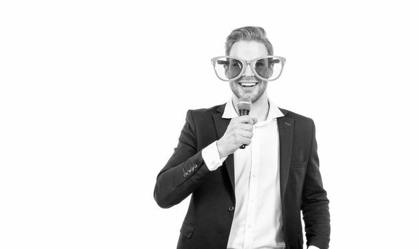 Vtipný muž v obchodní formalwear a party brýle držet mikrofon šťastný úsměv, showman - Fotografie, Obrázek