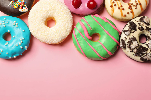 Different delicious glazed doughnuts on pink background, flat lay. Space for text - Valokuva, kuva