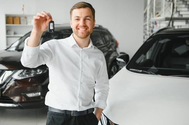 Yes, that's my new car. Customer in car dealership. Young man with keys in hand - Foto, Bild