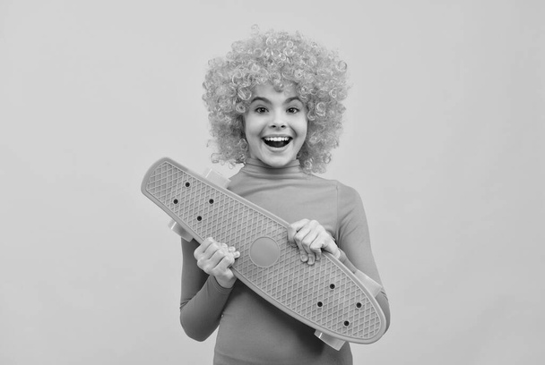 Happy cool girl with orange hair in pink poloneck smile holding pennyboard, skateboard - 写真・画像