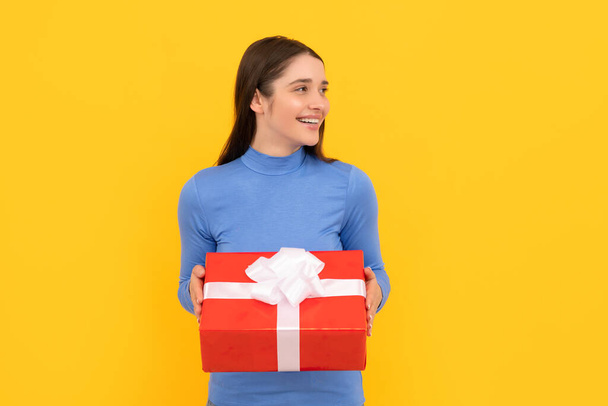seasonal sales. smiling girl with box on yellow background. boxing day. present and gifts buy - Foto, afbeelding