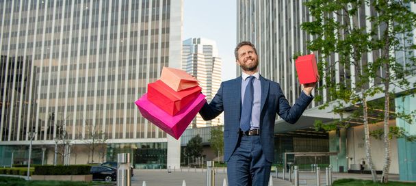 happy smiling mature businessman in suit hold packages and gift box outside the office, discount. - Foto, Imagen