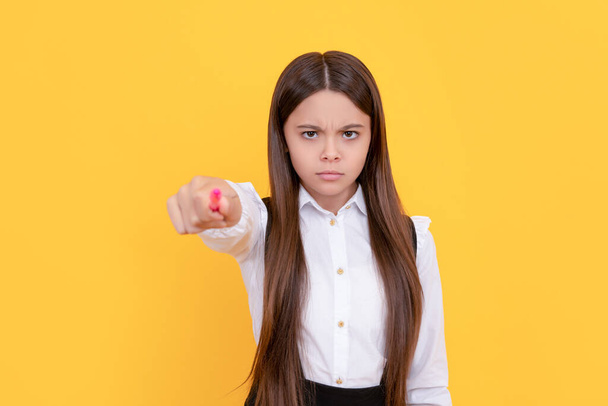 Серьезный хмурый школьница указывать ручку положить руку желтый фон, обратно в школу - Фото, изображение