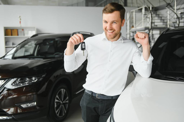 Yes, that's my new car. Customer in car dealership. Young man with keys in hand - Foto, Imagen