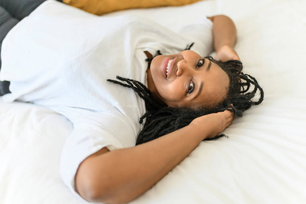 Portrait of an african woman lay on a white bed - Fotografie, Obrázek