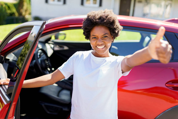 Young black woman with first red car with big thumb up - Foto, Bild