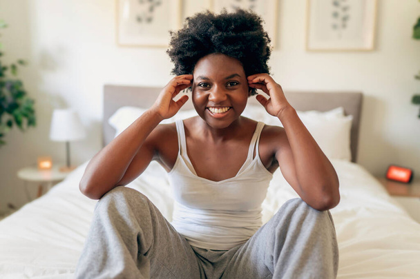 beautiful young African woman in tank top sit on bedroom - Photo, Image