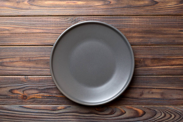 Top view of black plate on wooden background. Empty space for your design. - Foto, immagini