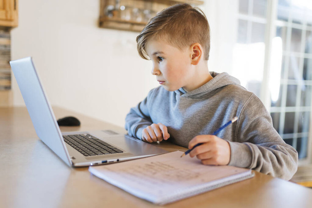 Teenager boy doing his homework at desk indoors - Фото, изображение