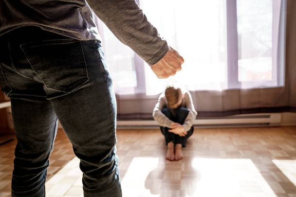 Sad child boy sit on the floor with father in front of him with hard look and close fist - Foto, afbeelding