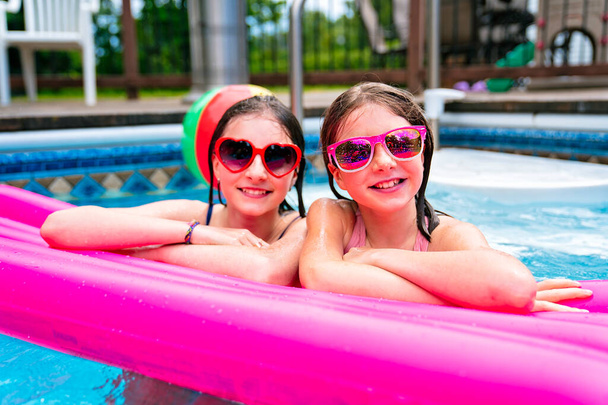 two sister having fun in Pool on the summer time - Фото, изображение